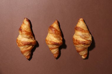 Kahverengi arka planda lezzetli kruvasanlar.