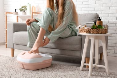 Kaplıca malzemeleri taşıyan bir kadın evde ayak banyosu yapıyor.