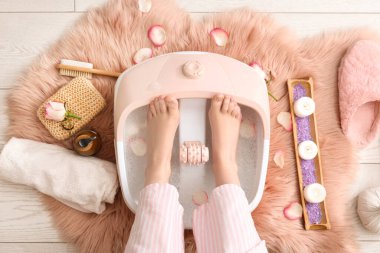 Ayak masajlı kadın bacakları ve yerde kaplıca malzemeleri.