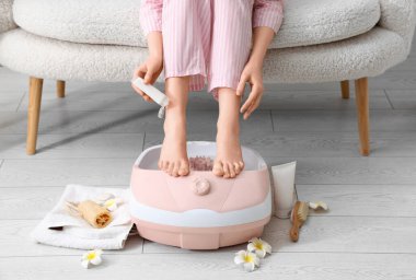 Masaj banyosu ve spa malzemeleri olan bir kadın bacağına krem sürüyor.