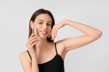 Beyaz arka planda kapatıcısı olan güzel genç bir kadın.