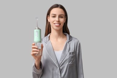 Gri arka planda ağız sulandırıcısı olan güzel bir genç kadın.