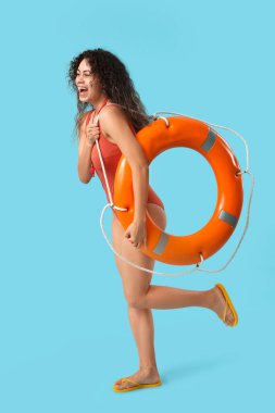 Mavi arka planda halka şamandırası olan güzel, mutlu, Afro-Amerikan kadın cankurtaran.