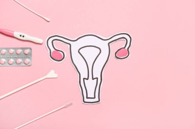 Pembe arka planda hamilelik testi, haplar ve Pap smear test araçları ile kağıt rahim