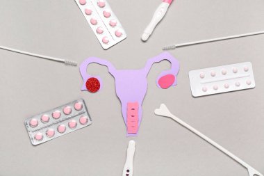 Pap smear test araçları ve gri arka planda haplar içeren kağıt rahim.
