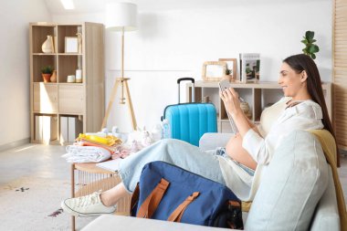 Hamile bir kadın doğum çantası için kontrol listesi yazıyor.