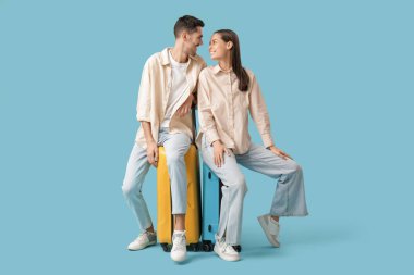 Mavi arka planda bavulları olan güzel, genç, mutlu turistler.