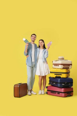 Pasaportları, biletleri ve sarı arka planda bir sürü bavulu olan mutlu turistler.