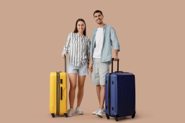 Kahverengi arka planda bavulları olan genç ve güzel turistler.