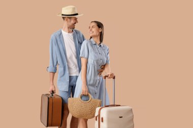 Kahverengi arka planda bavulları olan genç ve güzel turistler.