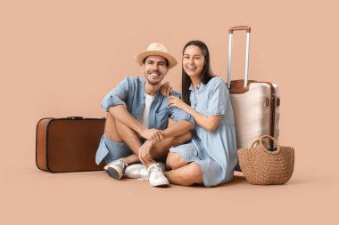 Güzel, genç, mutlu, bavulları kahverengi arka planda iki turist.