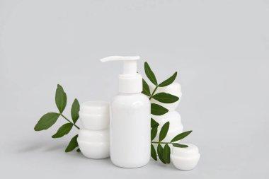 Gri arkaplanda kozmetik ürünler ve dallar