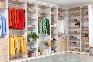 Soyunma odasında farklı kıyafetleri ve aksesuarları olan büyük gardırop.