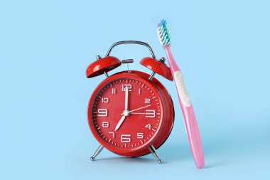 Mavi arkaplanda kırmızı alarm ve diş fırçası