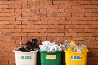 Kahverengi tuğla duvarlı farklı geri dönüşüm kutuları. Geri dönüşüm kavramı
