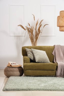 Yeşil kanepeli, puf ve pampa otlu rahat bir oturma odası.