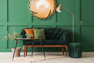 Yeşil kanepesi, masası ve altın aynası olan şık bir oturma odası.