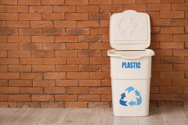 Tuğla duvarın yanında PLASTIC işareti olan boş çöp kutusu. Geri dönüşüm kavramı