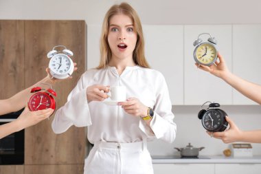 Elinde kahve fincanı ve elinde çalar saatlerle sürpriz bir genç kadın.