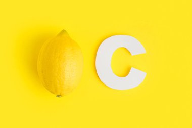 Kağıt C harfi ve sarı arka planda taze limon.