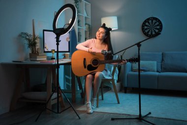 Gitarlı ve mikrofonlu kız öğrenci akşam evde takılıyor.