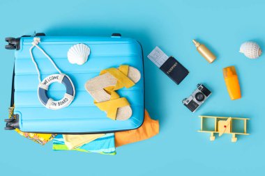 Plaj aksesuarları, kozmetik ürünleri, pasaport ve dekorlu bavul