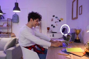 Akşam evde dizüstü bilgisayar kullanan erkek öğrenci