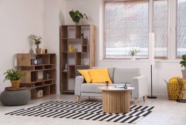 Rahat kanepesi, raf ünitesi, ev bitkileri ve sehpası olan modern bir oturma odası.