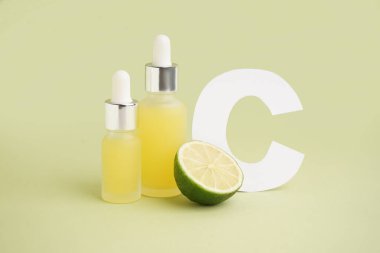 Renk arkaplanına bir şişe turunçgil yağı ve C harfi.