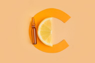 Renk arkaplanına C vitamini, limon dilimi ve C kağıt harfi ampülü