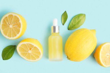 Bir şişe temel yağ ve arka planda taze limon.