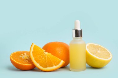 Bir şişe gerekli yağ ve arka planda taze narenciye meyvesi.