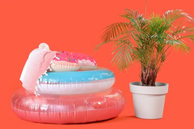 Kırmızı arka planda havlusu ve bitkisi olan şişme halkalar.