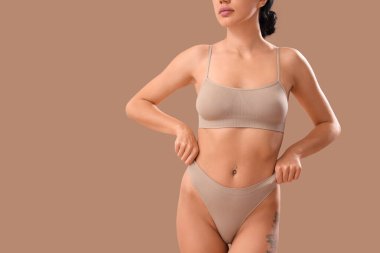 Bej arka planda açık renk iç çamaşırlı güzel bir kadın.