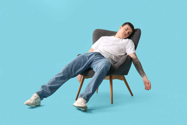 Уставший молодой человек спит в кресле на синем фоне