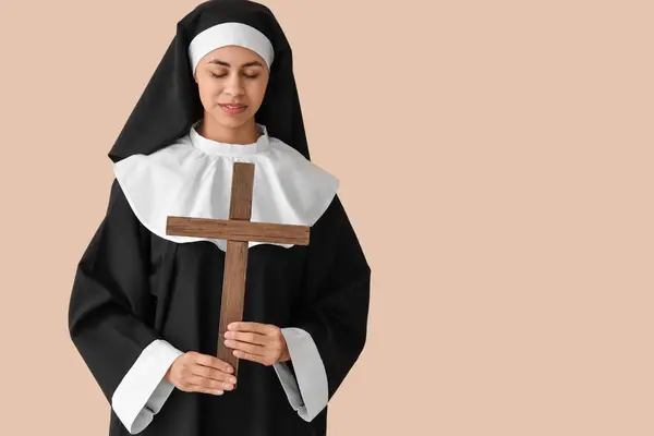 stock image Young nun with cross on beige background
