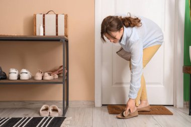 Genç bir kadın süet ayakkabılarını fırçayla temizliyor.