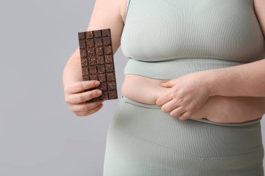 Hafif arka planda çikolatası olan şişman bir kadın, yakın plan. Diyet kavramı