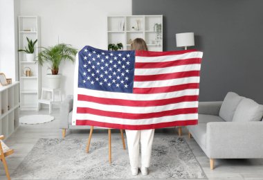Oturma odasında Amerikan bayrağı olan bir kadın.