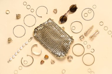 Güneş gözlüklü bir kadın çantası ve bej arka planda birçok farklı aksesuar.