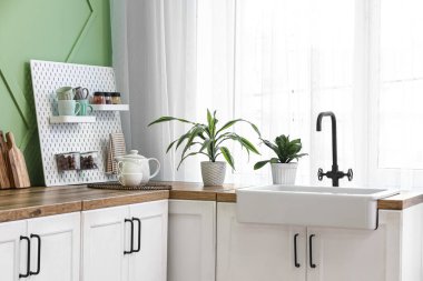 Tahta, ev bitkileri ve pencerenin yanındaki mutfakta lavabo.