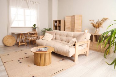 Oturma odasının içinde bej kanepe ve masalar var.