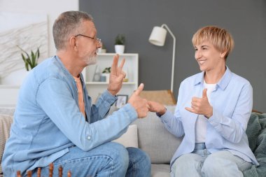 Evde kanepede işaret dili kullanan sağır ve dilsiz bir çift.