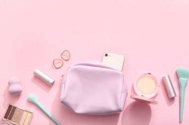 Cep telefonlu kozmetik çanta, makyaj ürünleri ve pembe arka planda aksesuarlar.