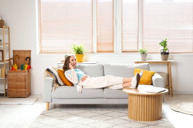 Oturma odasında cep telefonuyla konuşan genç ve güzel bir kadın.