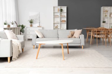 Gri koltukları, yemek masası ve raf üniteleri olan ışık odasının içi.