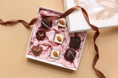 Kahverengi arka planda lezzetli çikolata şekerleriyle dolu bir kutu.