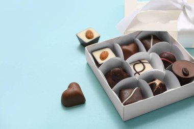 Mavi arka planda lezzetli çikolata şekerleri olan bir kutu, yakın plan.