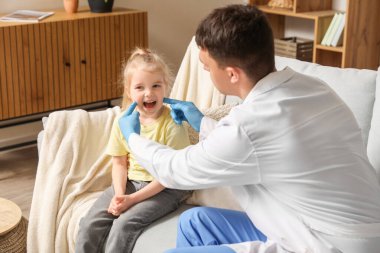 Erkek çocuk doktoru küçük kızı muayene ediyor.