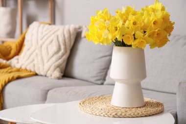 Oturma odasında vazo dolusu narsisli kahve masası.